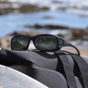A pair of Style Line Cocoons sunglasses with photochromic gray lenses resting on a surfboard, ready for a day of surfing.